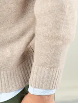 Sweater de lana merino color camel, de cuello redondo, mangas largas y diseño clásico, con pequeño logo bordado en el pecho.