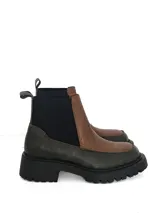 Botín tipo chelsea de cuero con diseño bicolor, combinando paneles en color marrón texturizado y gris oscuro liso. Cuenta con elásticos laterales negros y suela track robusta de goma.