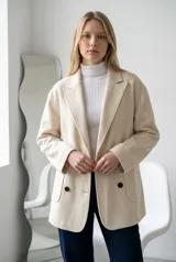 Tapado de paño color marrón, de corte oversize, con solapas clásicas, cierre frontal de doble botonadura y bolsillos laterales de parche.