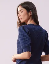 Cárdigan blanco tejido con escote en V, abertura frontal con botones y mangas cortas abullonadas con puño.