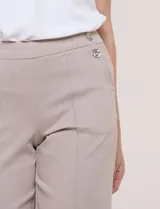 Pantalón crop blanco de corte recto con cintura ancha y botones decorativos laterales. Cuenta con bolsillos y pinzas frontales.