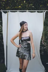 Vestido corto negro con diseño cut-out en la cintura, estilo strapless y ruedo decorado con flecos largos.