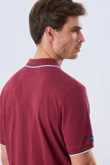 Remera polo de piqué azul marino, con cuello y puños de mangas cortas con ribete blanco en contraste, cierre frontal de dos botones y pequeño logo bordado en el pecho.