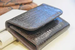 Billetera de cuero marrón con estampado de piel de serpiente, con cierre de broche a presión.