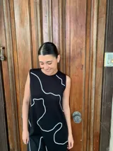 Vestido midi negro con estampado de líneas blancas, sin mangas y cuello redondo.
