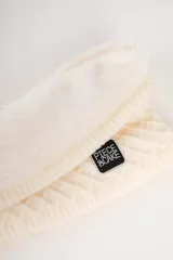Cuello de lana color crudo con diseño de rombos en relieve y etiqueta negra con logo de la marca.