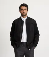 Chaqueta bomber azul marino lisa, con cierre frontal, cuello redondo y bolsillos laterales.