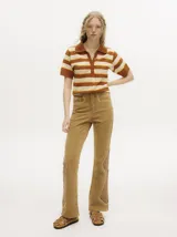 Pantalón de denim color tostado con tiro alto y corte oxford. Presenta detalles de apliques metalizados a lo largo de las costuras laterales y en los bolsillos.