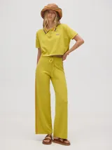 Chomba tipo crop de tejido de punto color verde lima, con cuello camisero con detalles de rayas en contraste, cierre frontal con botones y logo bordado en el pecho.