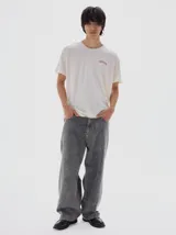 Remera gris oscura de algodón lavado, con cuello redondo, manga corta y corte oversize. Presenta un pequeño logo bordado en el pecho.