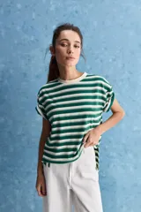 Remera de calce relajado con diseño a rayas horizontales blancas y verdes, hombros caídos y mangas amplias con vuelta. Presenta cuello redondo y ruedo trasero levemente más largo.