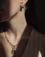 Aros pequeños de bronce con forma irregular y acabado liso, estilo huggie o argolla gruesa.