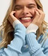 Blusa de punto color blanco con cuello alto y manga larga.