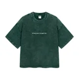 Remera de corte boxy, color verde oscuro con efecto lavado (acid wash), cuello redondo y manga corta ancha. Presenta un pequeño bordado frontal con el texto "Facha Posta".
