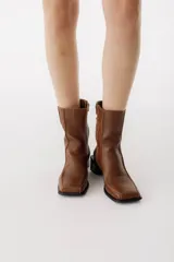 Bota corta de cuero color bordó, con punta cuadrada y taco bloque bajo. Cierre lateral con cremallera.