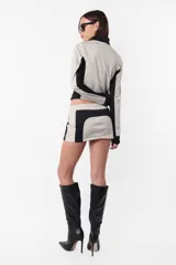 Minifalda deportiva de tiro bajo, color gris con recortes negros y estampa de logo a tono en el recorte trasero. Cierre invisible en el lateral.