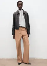 Jersey de punto fino color gris claro, de corte recto y manga larga, con cuello alto y detalle de lazada en el cuello.