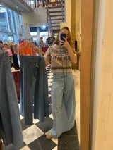 Pantalón de denim celeste claro, con cintura alta fruncida con elástico (smock) y dos botones decorativos en el lateral superior. El tejido es de algodón 100%.