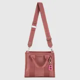 Tote bag color marrón, con diseño funcional, cierre en el compartimento principal, bolsillo interior, asas cortas y correa ajustable extraíble. Incluye un dije colgante con la letra B en color verde lima.