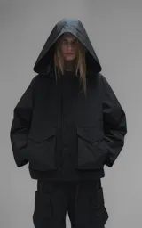Campera técnica liviana de microfibra negra con acabado mate, capucha ajustable, cierre frontal oculto bajo solapa, bolsillos frontales con solapa y cordón ajustable en la cintura.