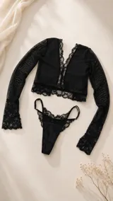 Conjunto de lencería negro de encaje y tul, compuesto por un bralette de manga larga con escote en V y una bombacha tipo tanga con detalles de encaje.