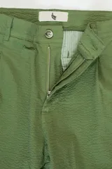 Pantalón verde oliva de algodón con textura seersucker, bolsillos laterales y traseros, cierre con botón y cremallera, parche con logo.