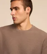 Remera color crema, de corte holgado, con cuello redondo y mangas cortas.