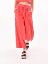 Pantalón de corte amplio y fluido, color rojo, con cintura elástica y cordón ajustable. Presenta aberturas laterales en el ruedo y bolsillos laterales.
