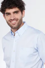 Camisa de manga corta color celeste claro, con cuello abotonado (button-down) y un bolsillo de parche en el pecho.