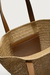Bolso tipo shopper de acabado trenzado color tostado, con compartimento principal sin cierre, bolsillo plano interior y dos asas de mano de cuero sintético marrón.