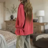 Blusa color beige de corte holgado, cuello alto con volados y mangas largas abullonadas con elástico en los puños.