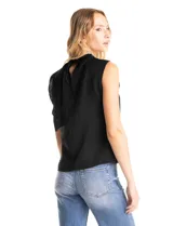 Blusa sin mangas color blanco, confeccionada en crepe con acabado satinado. Presenta un cuello alto decorado con mostacillas y una sobrecapa drapeada en el frente. La espalda cuenta con una abertura tipo gota y cierre de botón.