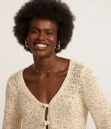 Cardigan color crema confeccionado en tejido de punto con algodón BCI más sostenible. Tiene cuello en V, manga larga y cierre frontal con dos botones.