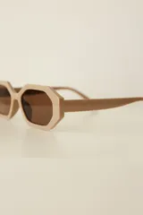 Lentes de sol con armazón de policarbonato en color beige y diseño hexagonal, con cristales oscuros con protección UV400.