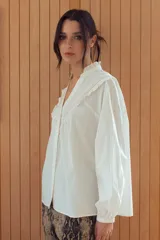 Camisa a rayas verticales rojas y blancas con cuello mao y mangas 3/4 abullonadas. Presenta detalles de puntilla blanca en el canesú. Cierre frontal con botones.