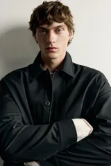 Sobrecamisa negra de corte relaxed fit, confeccionada en tejido de algodón con elasticidad. Cuenta con cuello solapa, manga larga con puño abotonado, bolsillos de vivo en la cadera y cierre frontal de botonadura.