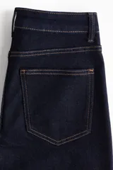 Pantalón de jean tiro alto, color azul oscuro, de corte ancho y pierna recta. Presenta costuras en hilo contrastante y grandes bolsillos parche delanteros y traseros.