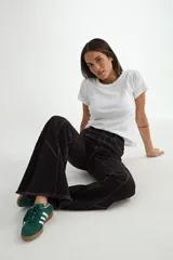 Jean de corte flare en color negro, con costuras verticales decorativas en contraste y ruedo deshilachado.