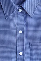 Camisa de corte oversized confeccionada en popelina de algodón con diseño de microcuadros. Presenta cuello clásico, bolsillo de parche en el pecho, cierre frontal con botones, hombros caídos y mangas largas con puños abotonados. Incluye canesú con pliegue en la espalda y bajo recto con aberturas laterales redondeadas.