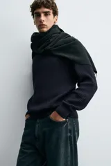 Sweater de punto en canalé color negro, de corte regular fit, cuello redondo y manga larga con terminaciones en rib.