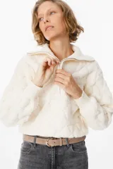 Sweater de tejido acolchado con diseño de rombos, color beige, con cuello polo y cierre frontal parcial. Presenta puños y cuello en tejido acanalado, con mangas largas y corte cropped.