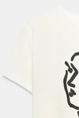 Remera de algodón de corte regular con cuello redondo y manga corta. Presenta un estampado frontal con un dibujo lineal de un rostro y la firma de Henri Matisse en color azul.