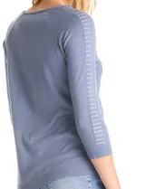Buzo de tejido fino en color blanco, con cuello redondo y mangas raglán tres cuartos. Presenta una línea de tachas decorativas a lo largo de las mangas.