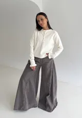 Sweater de punto color marrón chocolate, con cuello redondo y cierre frontal parcial con botones. Presenta mangas largas con puños acampanados y detalle de volados.