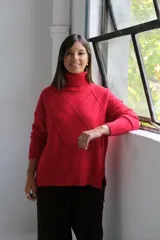 Polerón de punto color rojo con cuello alto y diseño de rombos texturizados. Presenta mangas largas con puños acanalados y un corte holgado con ruedo asimétrico.