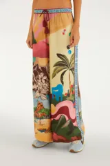 Pantalón palazzo de viscosa con estampado ilustrado de escenas de Río de Janeiro, palmeras, flores, playa y una franja lateral con inscripciones. Cuenta con cintura elastizada y cordón ajustable con borlas.