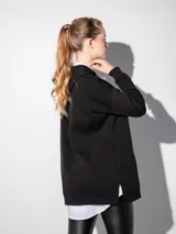 Canguro blanco oversize con capucha, cordones y bolsillo tipo canguro.