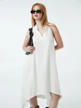 Vestido blanco con escote en V, cuello camisero y corte asimétrico.