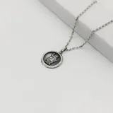 Conjunto de collar con cadena de eslabones plateados y dije redondo con la imagen de San Expedito en relieve.