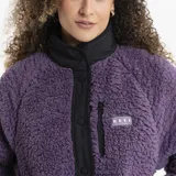 Campera de polar tipo corderito en color violeta, con cuello alto, cierre frontal con botones a presión y detalles en negro. Cuenta con un bolsillo frontal con cierre y logo de la marca.